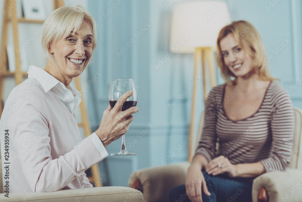 Elderly woman drinking wine in daughter company Elderly woman drinking wine in daughter company