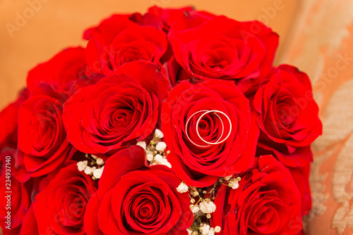 2 wedding rings on a bouquet of red roses