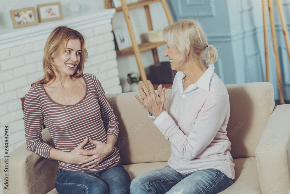Emotional daughter pleasing mother with news about pregnancy