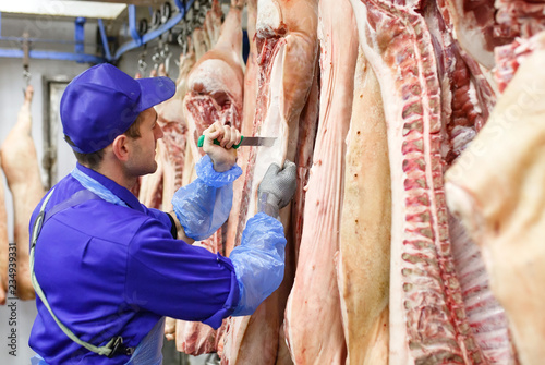 Butcher cutting pork at the meat manufacturing.