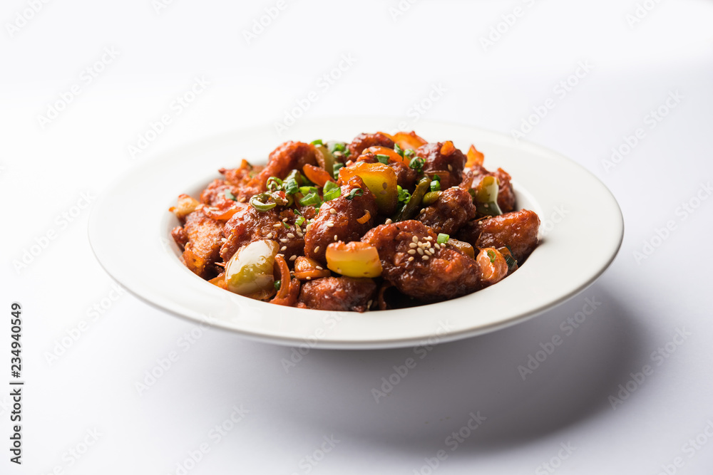 Indian Chilli Chicken dry, served in a plate over moody background. Selective focus