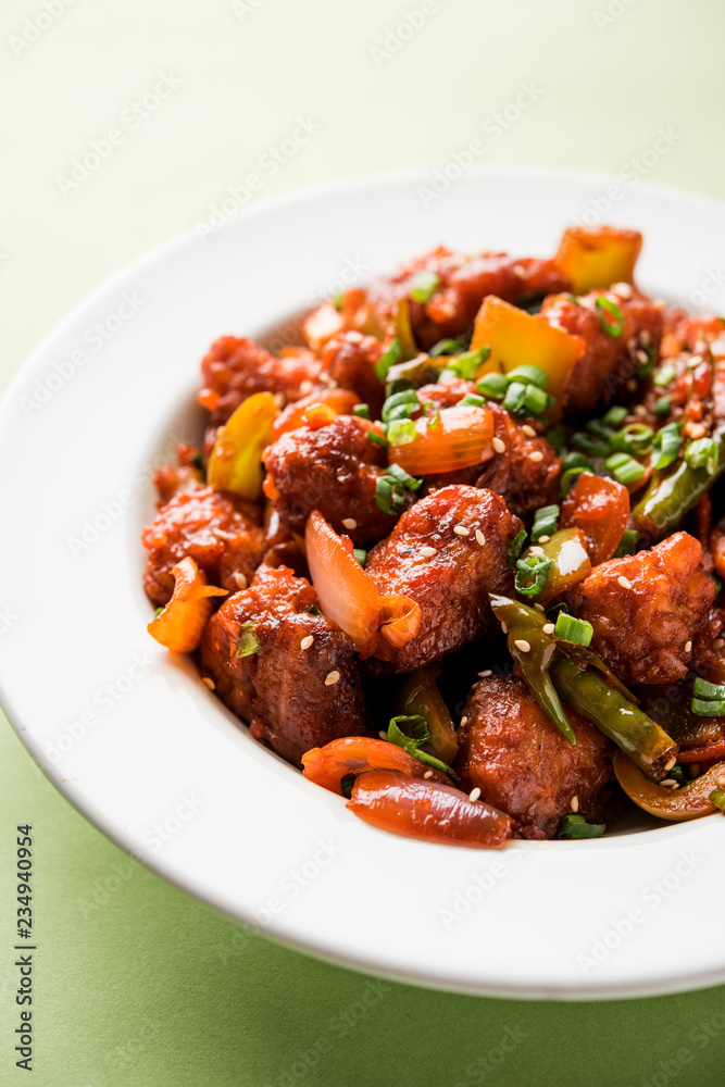 Indian Chilli Chicken dry, served in a plate over moody background. Selective focus