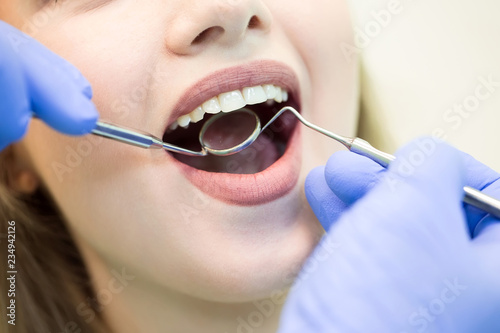 Close-up picture of young woman sitting in the dentist's chair with opened mouth at dentist's office while having examination.