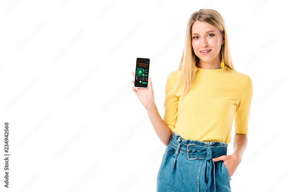 attractive young woman holding smartphone with marketing analysis app and smiling at camera isolated on white