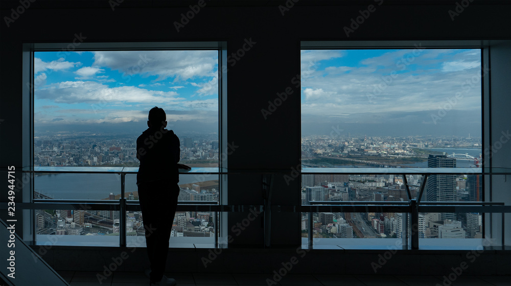 Fototapeta premium Silhouette of a man overlooking Osaka city.