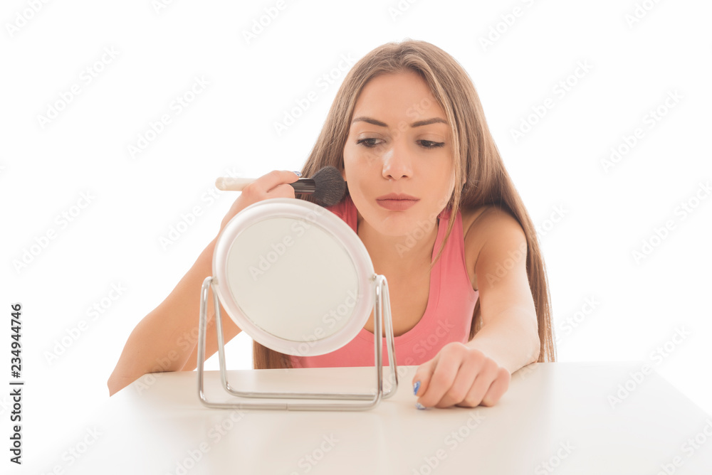 Beautiful young woman applying make up with a brush on white background Beautiful young woman applying make up with a brush on white background