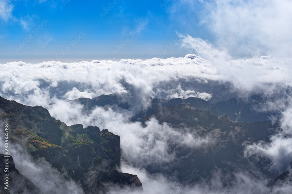 Dense clouds over mountains range on sunny day on Portuguese island of Madeira
