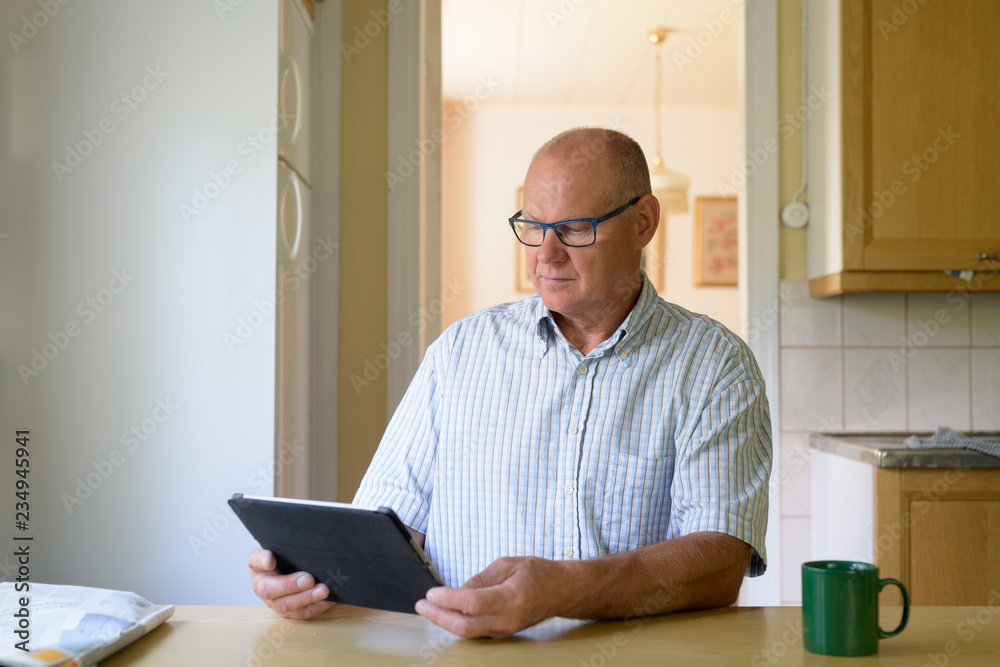 Senior Man Using Digital Tablet Near The Window Senior Man Using Digital Tablet Near The Window