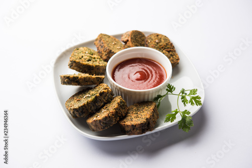 Cilantro cake or Kothimbir Vadi is a popular maharashtrian cuisine made with cilantro leaves. served with tomato ketchup. selective focus photo