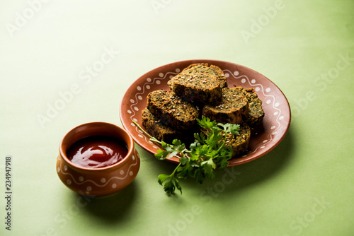Cilantro cake or Kothimbir Vadi is a popular maharashtrian cuisine made with cilantro leaves. served with tomato ketchup. selective focus photo