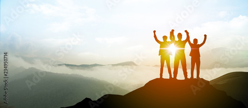 Silhouette of Business team show arm up on top of the mountain. Leadership and success Concept. photo