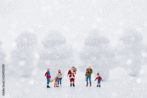 Miniature people in Christmas Theme. Santa Claus giving Christmas gift to children on Christmas day