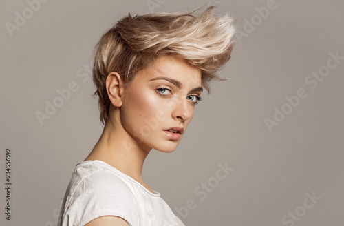 Canvas Print Portrait of young girl with blond fashion hairstyle looking at camera isolated o