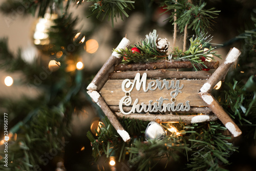 Festive Holiday Photo Banner Image with Cute Wooden Arrow Ornament with Merry Christmas in Script Font inside Christmas Tree with Bright White Lights with Blurred Background Seasonal Idea
