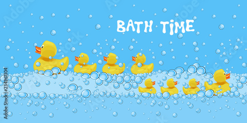 Set of cute rubber duck toys swimming in the bath water with soap bubbles.