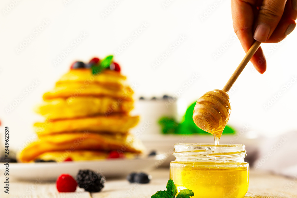 Honey with wooden honey dipper on wooden table