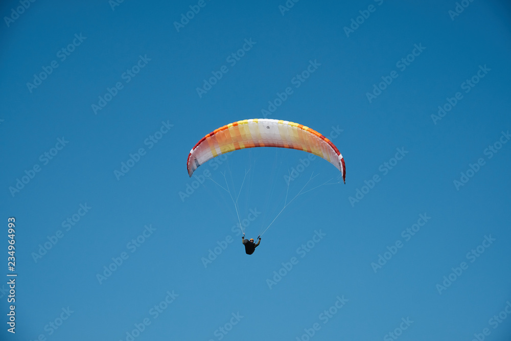 Paraglider is flying in the blue sky. Paragliding in the sky on a sunny day. Paraglider is flying in the blue sky. Paragliding in the sky on a sunny day.