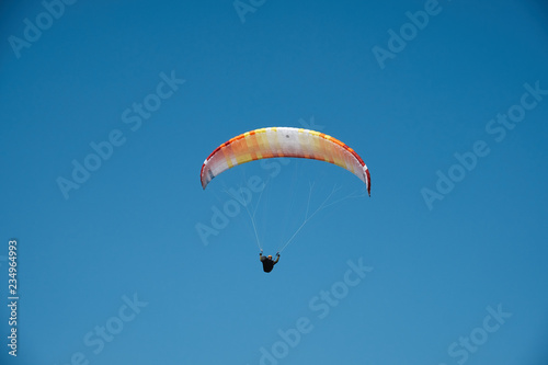 Paraglider is flying in the blue sky. Paragliding in the sky on a sunny day.