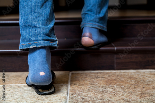 Feet in jeans and holey socks go up stairs
