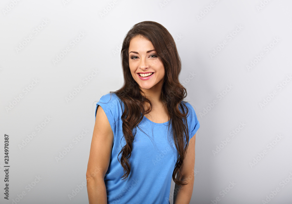 Beautiful calm woman looking with happy smile in blue shirt with long curly hairstyle. Closeup portrait with empty copy space Beautiful calm woman looking with happy smile in blue shirt with long curly hairstyle. Closeup portrait with empty copy space