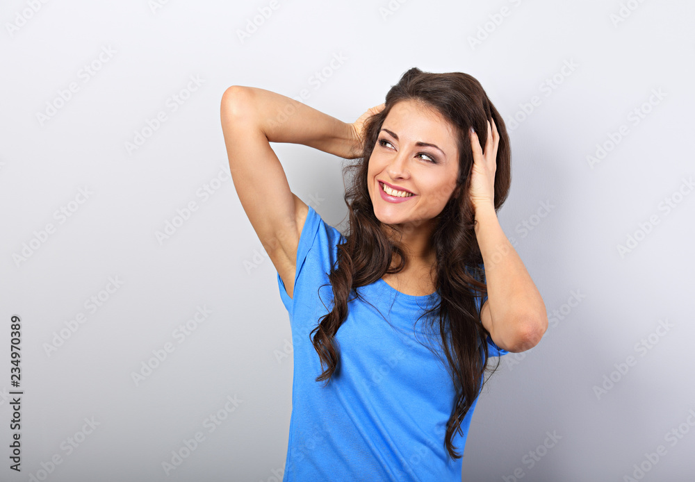 Beautiful thinking woman holding the head the hands and choosing something in blue shirt with long curly hairstyle. Closeup portrait. Beautiful thinking woman holding the head the hands and choosing something in blue shirt with long curly hairstyle. Closeup portrait.