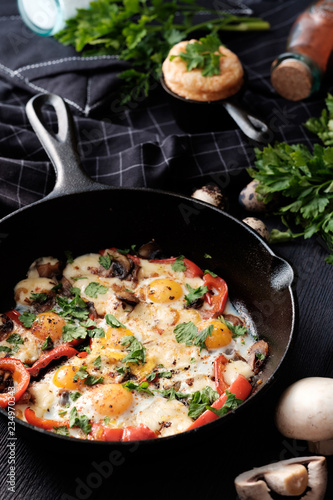 Fried eggs with bacon, mushrooms, bell peppers and greens
