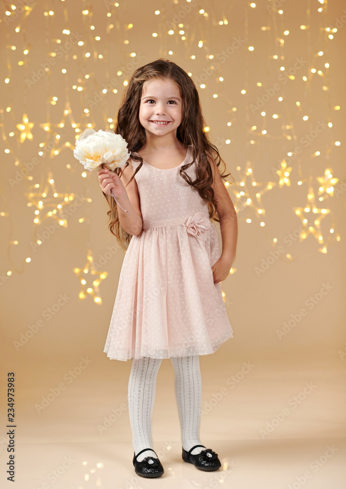 girl child is in christmas lights, yellow background, pink dress girl child is in christmas lights, yellow background, pink dress