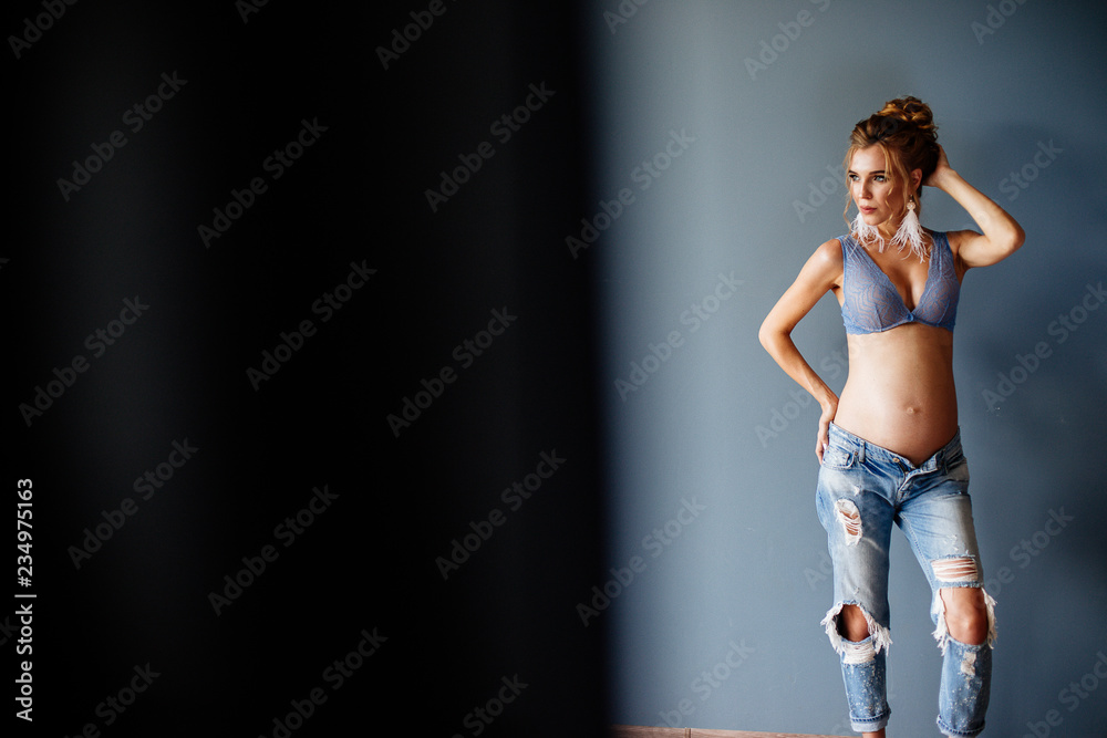 Beautiful pregnant young woman near the wall.