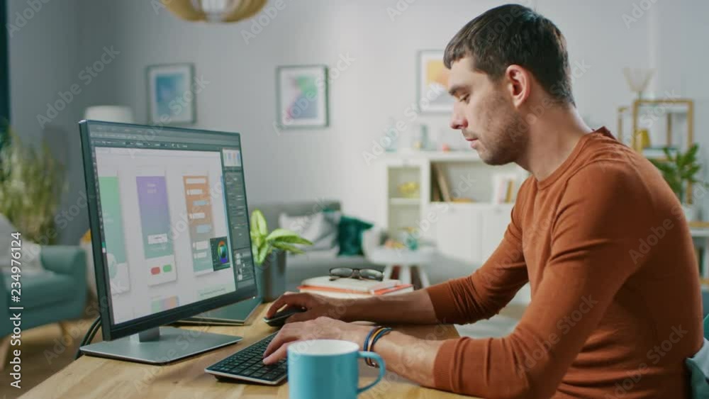 Handsome Software Engineer Works on a UX / UI Mobile App Template, Uses Personal Computer. Freelance Programmer Working from Cozy Living Room.