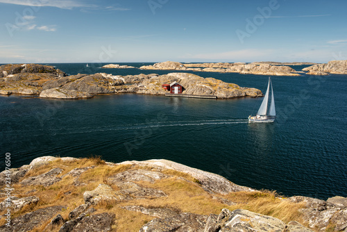 Sea landscape with sailboat and rocky coastline on the South of Sweden. Southern coastline of Sweden with view at sailing-ship and rocky islands.