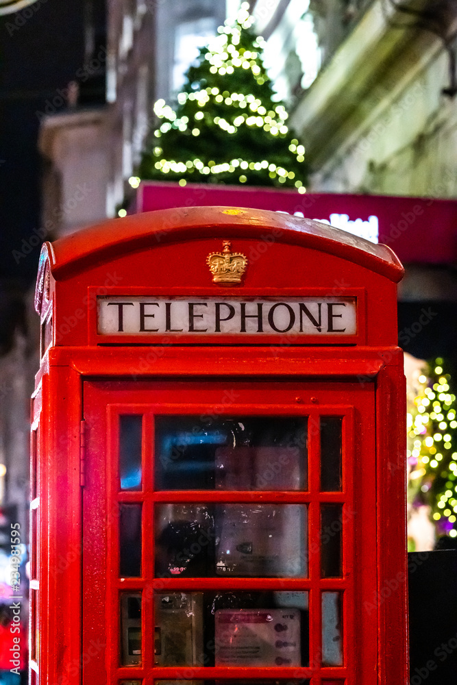 Iconic famous telephone box with Christmas decorate tree at the night in London Iconic famous telephone box with Christmas decorate tree at the night in London