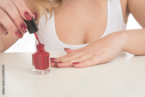woman painting her nails on her hands with red nail polish