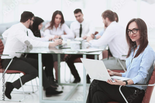 Executive businesswoman with laptop on blurred background business team