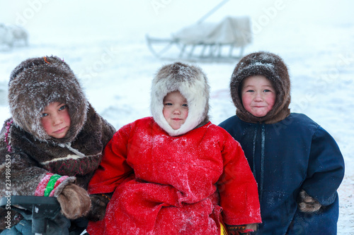 A resident of the tundra, indigenous residents of the Far North, tundra, open area, children ride on sledges, children  in national clothes photo