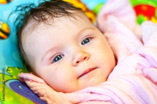 Cute and healthy smiling mildly happy positive newborn infant Caucasian baby girl with deep blue eyes. Healthy infant child concept.