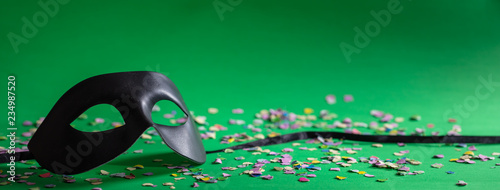 Carnival mask and confetti on green background