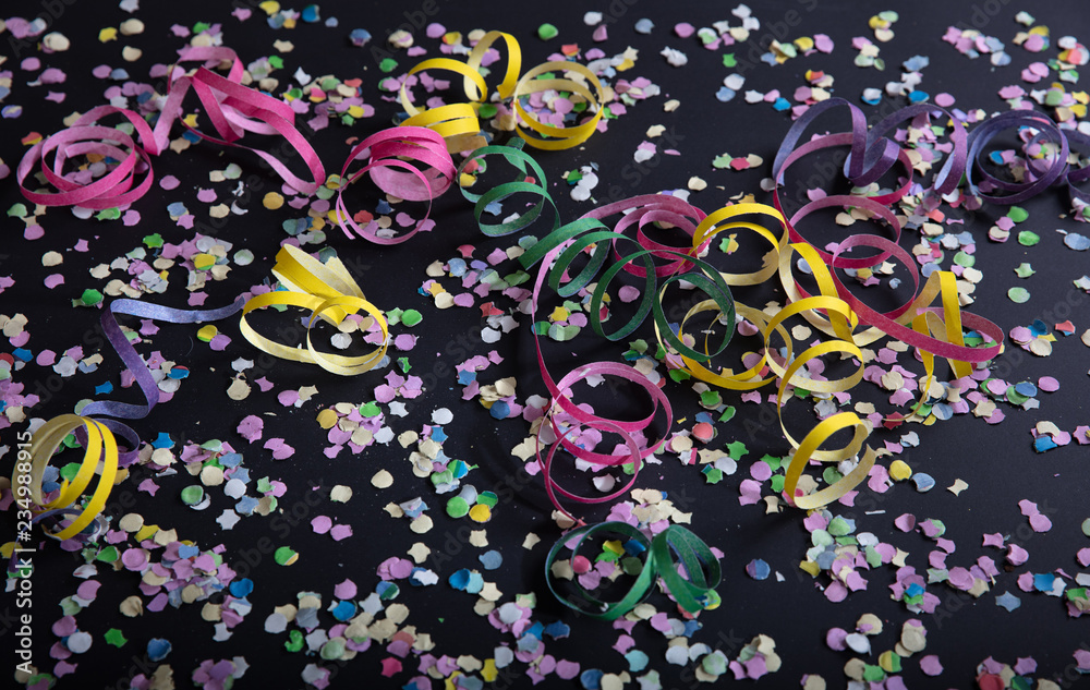 Carnival or birthday party, confetti and serpentines on black background