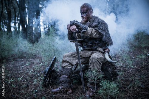 viking with red beard with armor shield and sword in the battle field photo