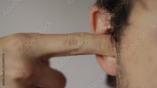 Close-up portrait of a young man plug his ear.