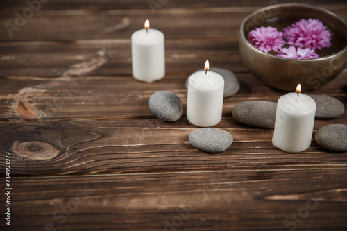 Singing bowl with candles with pebbles on dark wooden background