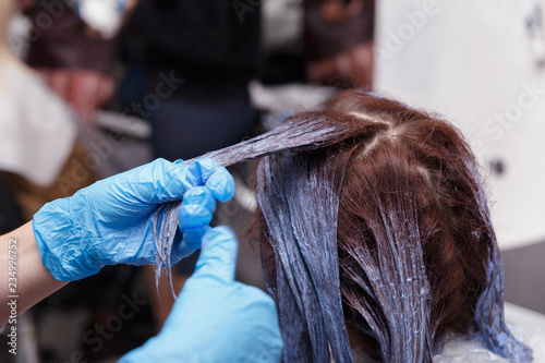 Woman dyeing hairs in dark color.