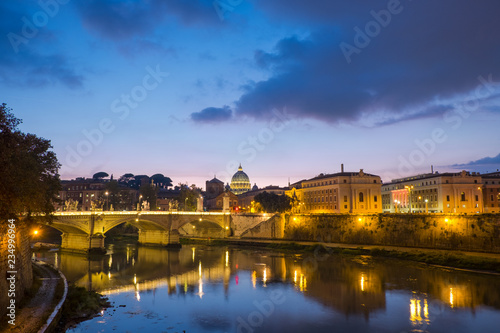 View of Rome at dusk, Vittorio Emanuele bridge, cupola of Saint Peter's Dome and Vatican, with waters of Tiber river in the front