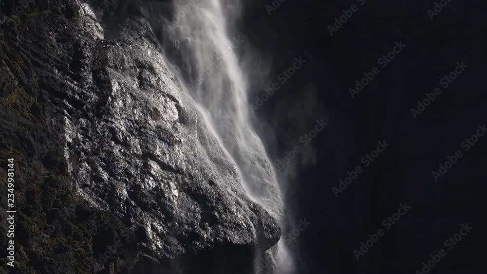 Beautiful slow motion detail of Gavarnie Falls at Cirque de Gavarnie, Pyrenees, France. Sunlit water and mist on rocky cliff face.