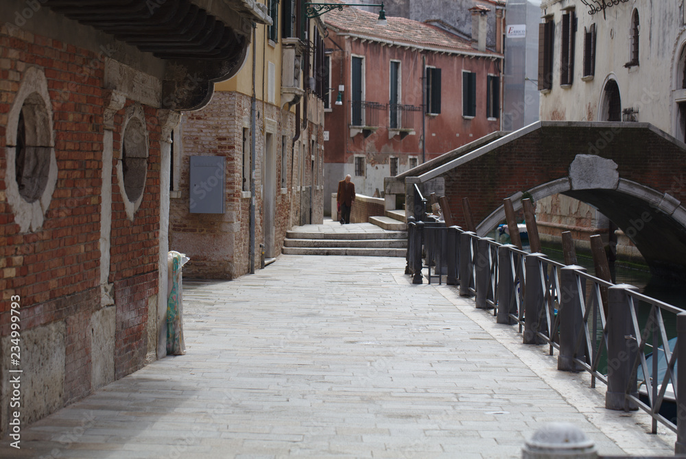 Fototapeta premium Old man walking up road near canal in Venice on April 5, 2018 (5072)