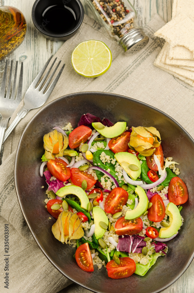 Fresh healthy summer salad with quinoa, avocado and cherry tomatoes. Fresh healthy quinoa salad on wooden background close up. Food and health. Superfood. 