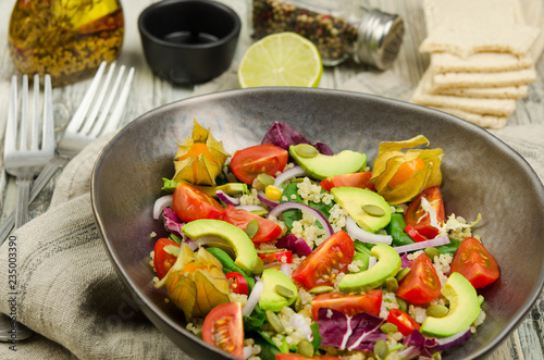 Fresh healthy summer salad with quinoa, avocado and cherry tomatoes. Fresh healthy quinoa salad on wooden background close up. Food and health. Superfood. 