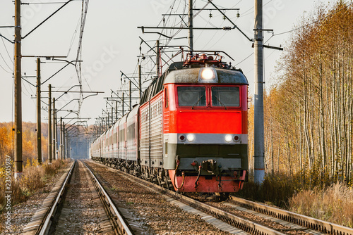 Passenger train approaches to the station at autumn morning time.