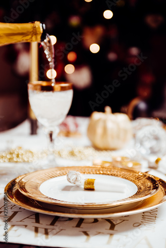 New year table setting with exclusive and luxury golden cutlery  over a tabletop with celebrations world   new year  against a background with great light and bokeh.