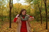 Young girl in coat standing on yellow leaves in Park in autumn.