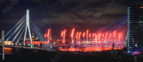 Colorful fireworks over river Daugava on Latvia's 100th birthday. Independence day celebration in Riga city with panoramic view over the old town and cable bridge. Light show in Riga city.